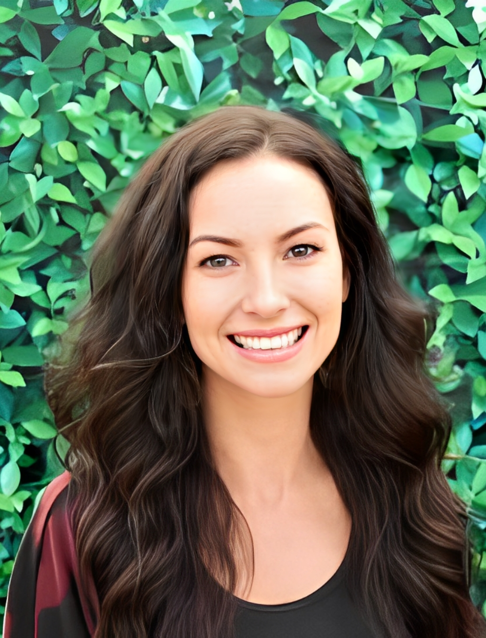 Smiling woman in front of leafy background.